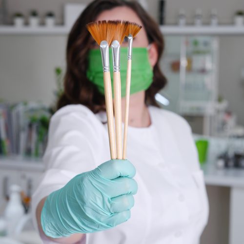 Cosmetologist with Fan Brushes for Facial Treatments