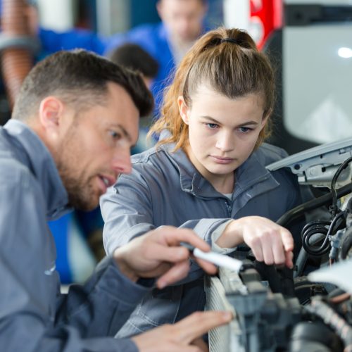 woman as a mechanic apprentice in auto repair shop